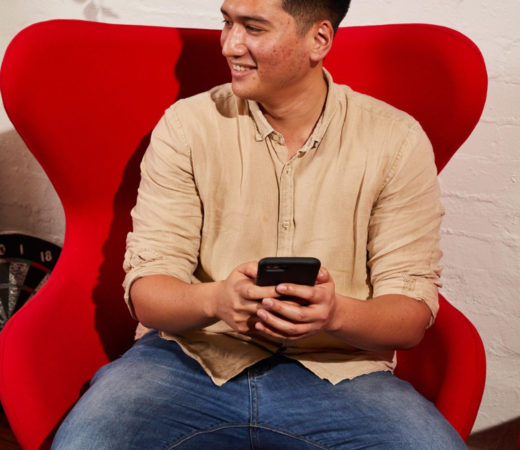 An image of a man smiling and looking to his right as he holds a phone