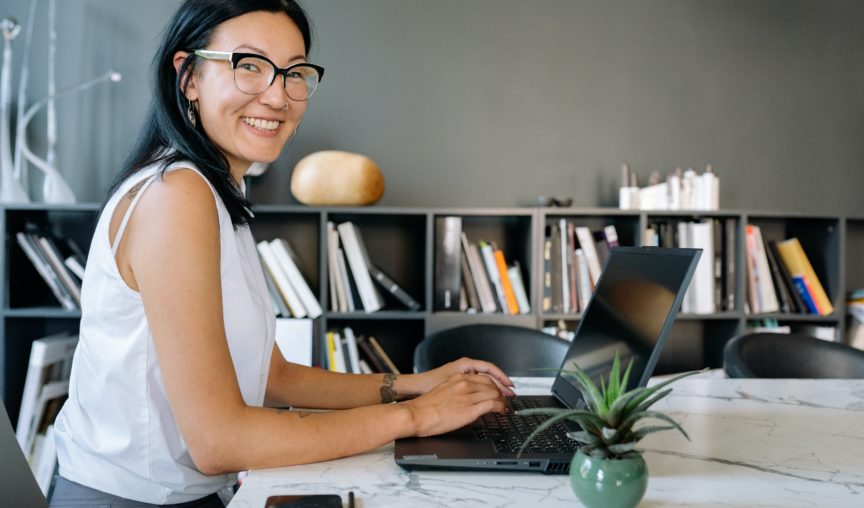 woman sitting at her desk typing and smiling