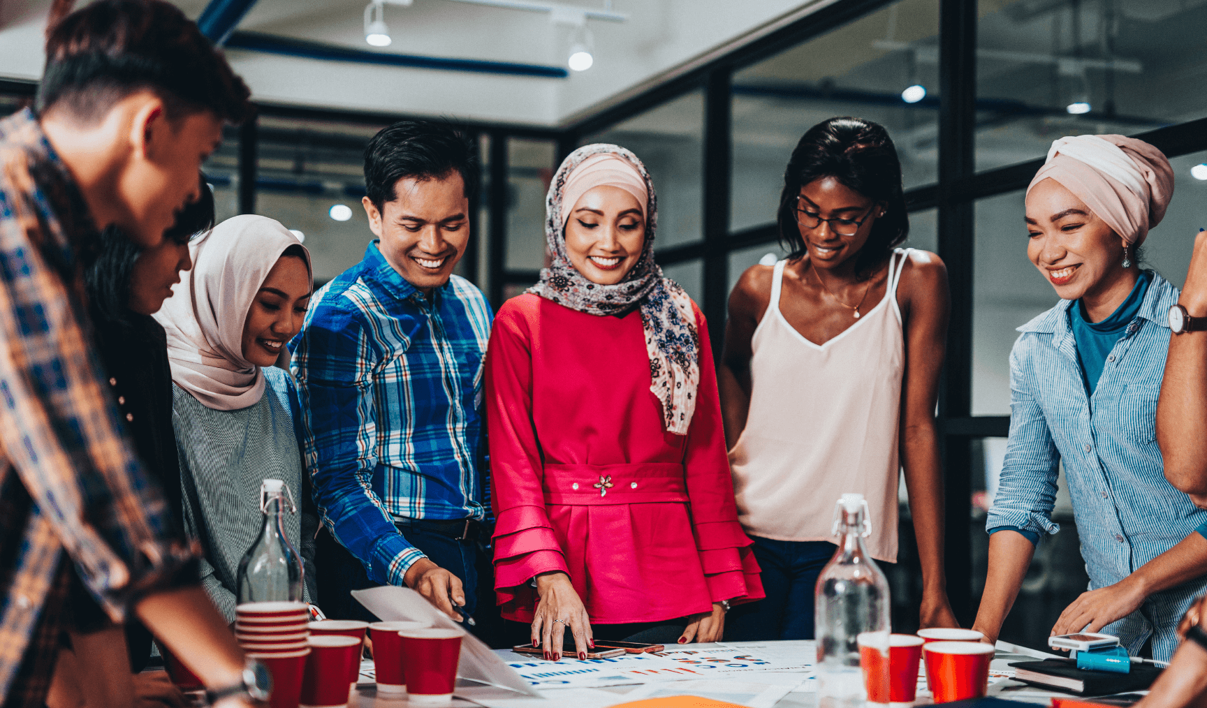 a group of colleagues looking down at a table and smiling
