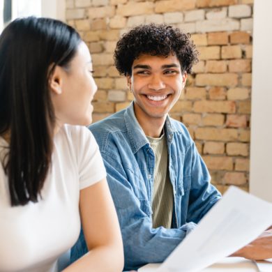 An image of two cheerful colleagues smiling at each other