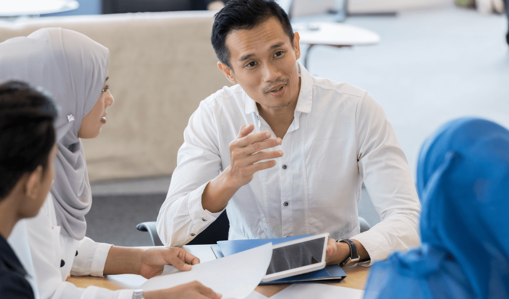 A group of professionals in a meeting, with one individual leading the discussion while others listen attentively