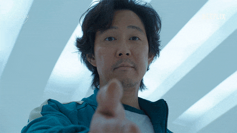 A character from Squid Game extends their hand in a gesture of offering help. A subtitle, "Wanna do this together?"