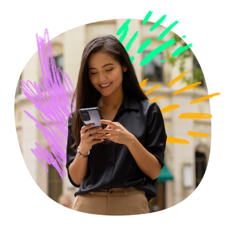 An image of a woman in smart casual attire, smiling at her phone set in a colorful background