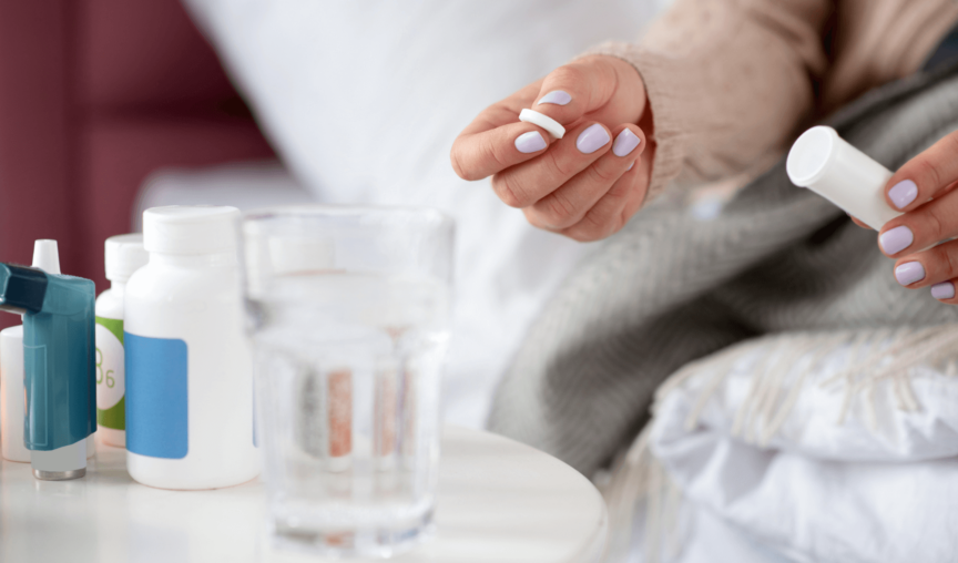 woman holding her medicine with a glass of water on the table