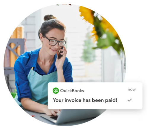 Small business owner receiving QuickBooks notification of paid invoice on laptop