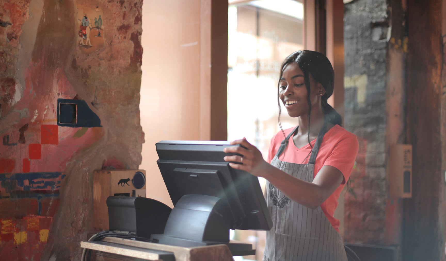 Woman stands working at a till in a cafe