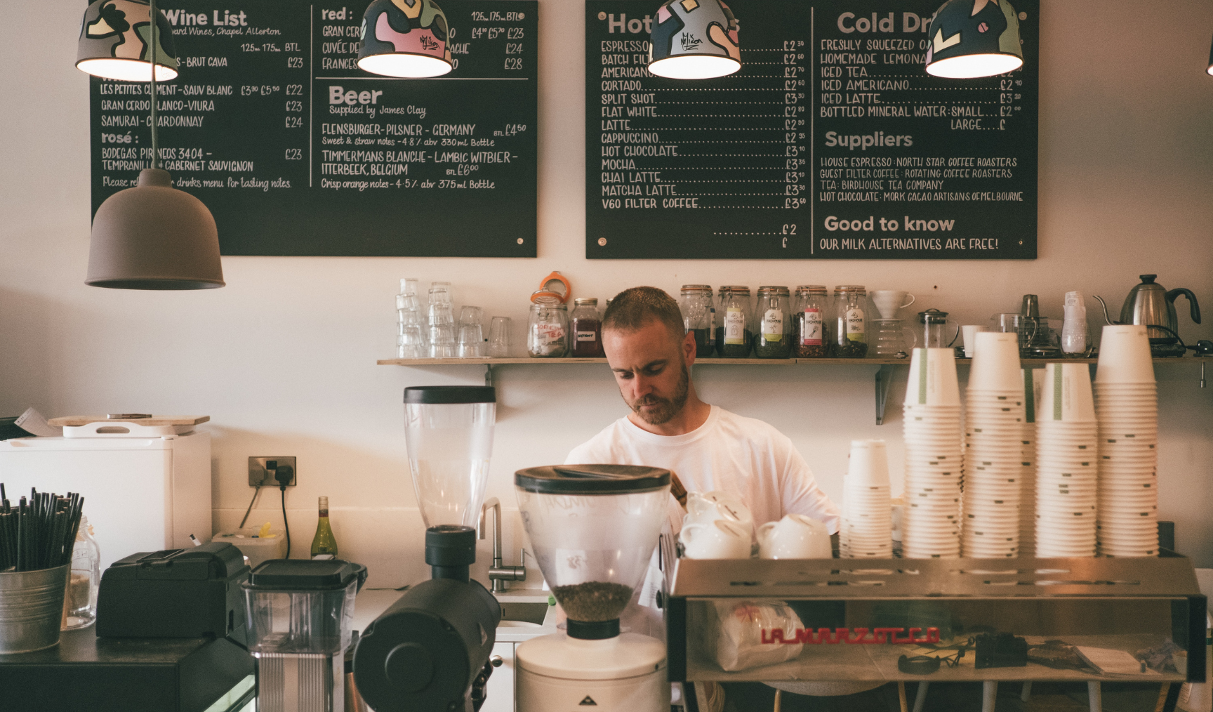Man stands at coffee machine in a cafe, making coffee