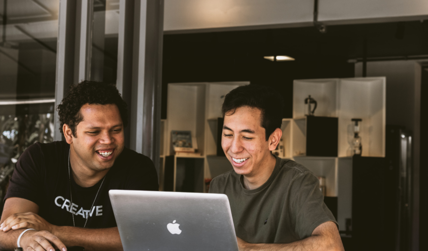 Two men sitting at a laptop chatting