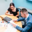 Businessman and businesswoman in the office working together, paperwork and using laptop.
