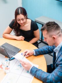 Businessman and businesswoman in the office working together, paperwork and using laptop.