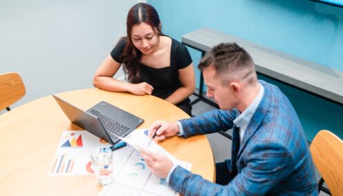 Businessman and businesswoman in the office working together, paperwork and using laptop.