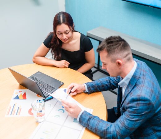 Businessman and businesswoman in the office working together, paperwork and using laptop.