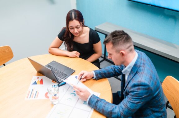 Businessman and businesswoman in the office working together, paperwork and using laptop.