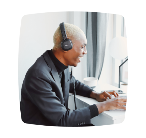 A man wearing headphones, smiling as he works