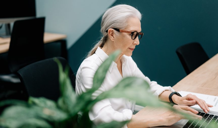 Older employee sitting at her desk in the office