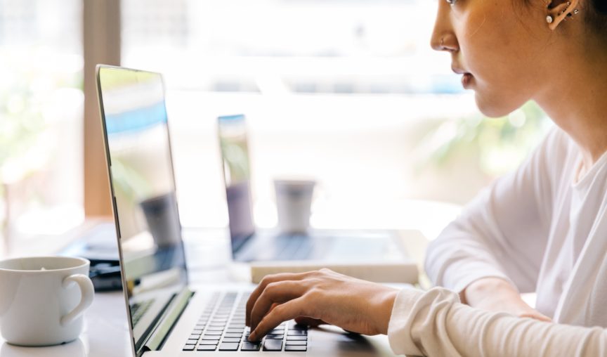 woman typing on her laptop at a cafe
