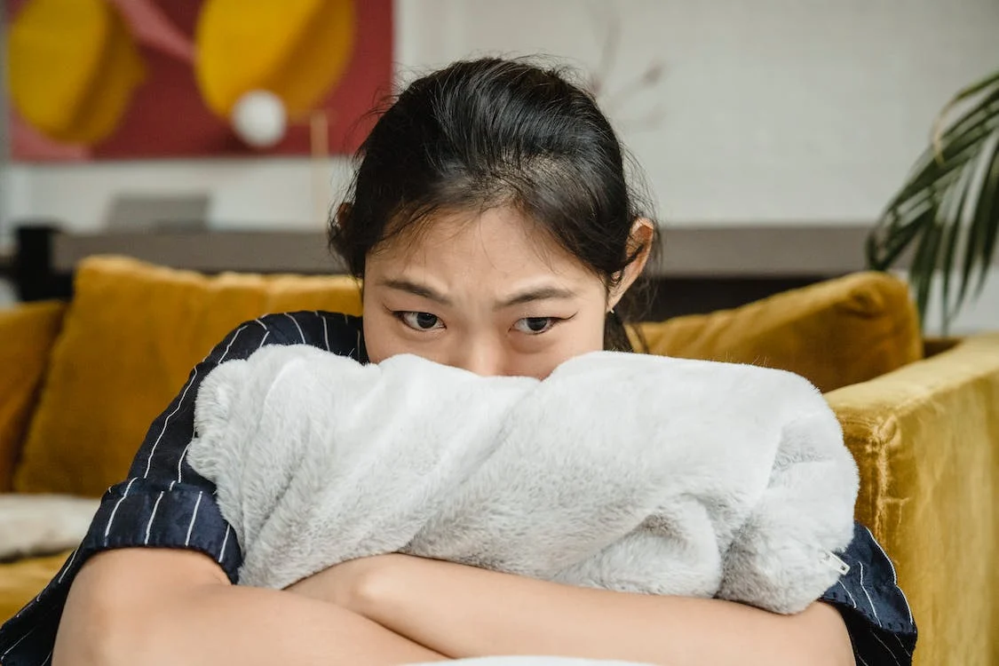 woman hugging a pillow at home looking sad