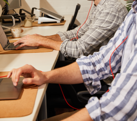 An image showing two men in long sleeves working on their laptop