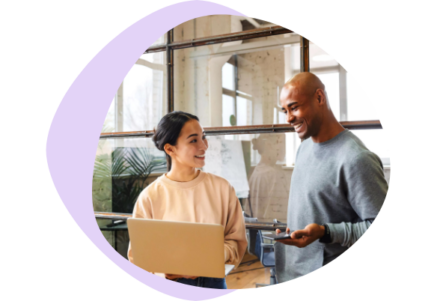 An image of two colleagues in the office, smiling over a discussion