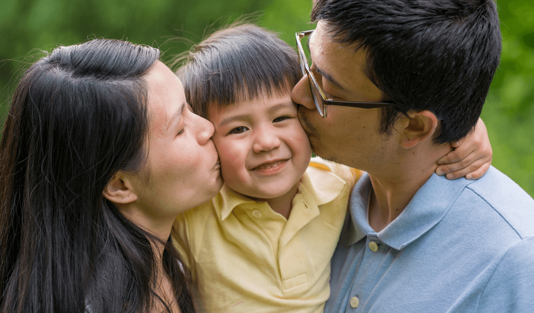 mum and dad kissing a little boy on his cheeks between them