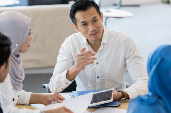 A group of professionals engaged in a discussion at a meeting table.