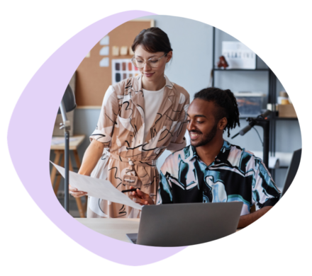 An image of two colleagues in graphic shirts, the woman discussing a project to the man