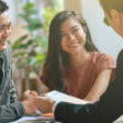A smiling couple sits across from a professional in a business setting, engaging in a friendly discussion.