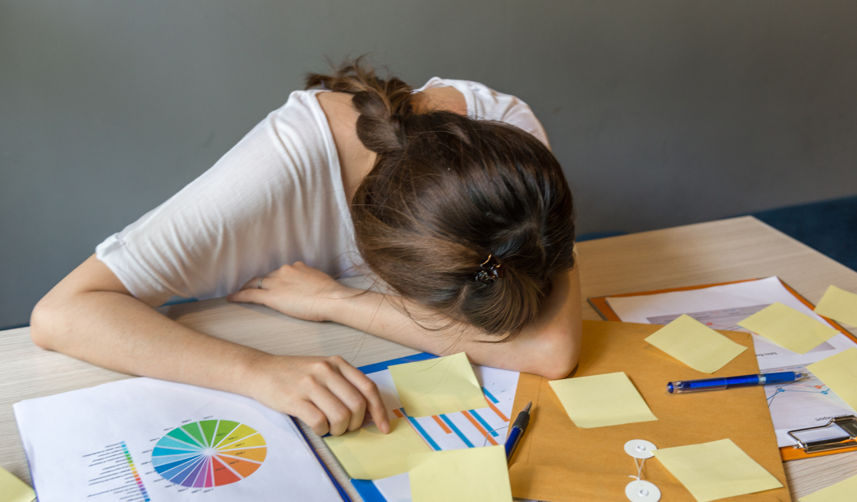 woman lying with her face down on her arm at her work desk