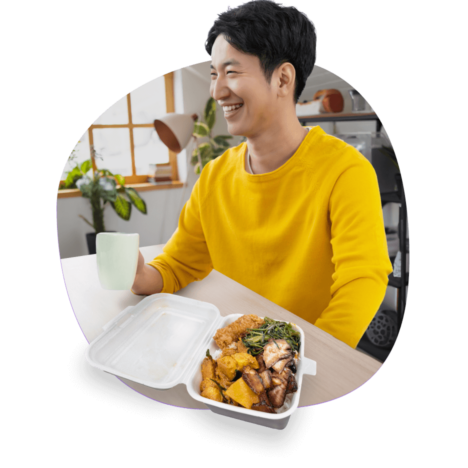 A smiling man in yellow, enjoying a cup of drink and cai fan