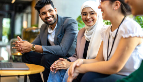A group of colleagues sitting together in a relaxed office environment, smiling and engaged in conversation