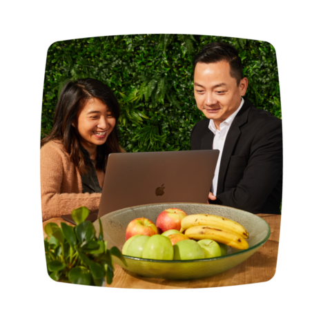 An image of two colleagues smiling as they work in a relaxed outdoor setting
