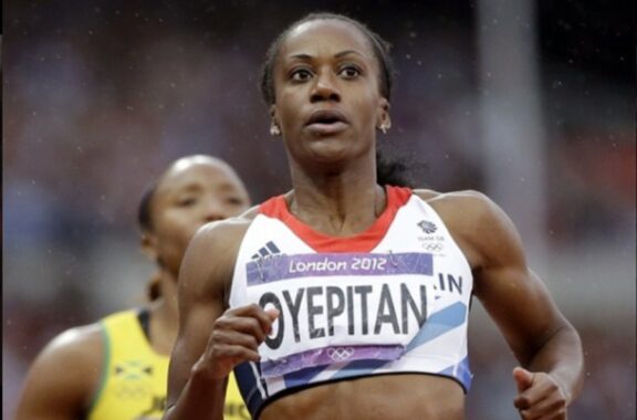 The image shows a female athlete, Abi Oyepitan, competing in a track event during the 2012 London Olympics.