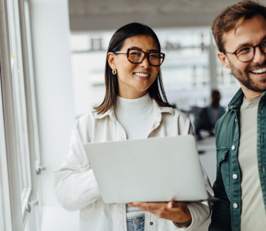 Business woman holding a laptop and standing with her colleague