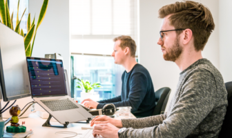 Two men sitting at their desks working on computers