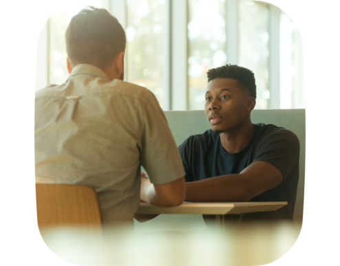A photo of two people sitting across from each other at a table, engaged in a serious conversation
