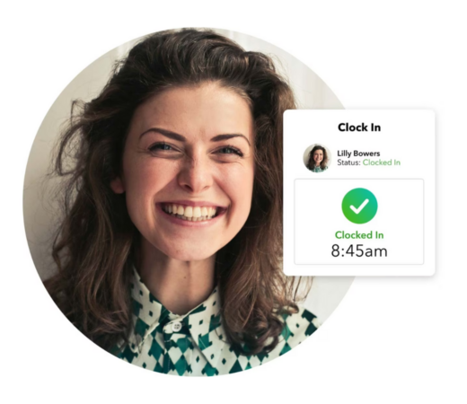 A close-up photo of a smiling woman with curly hair, wearing a patterned blouse. A digital overlay shows a "Clock In" notification for "Lilly Bowers," indicating she has clocked in at 8:45 am